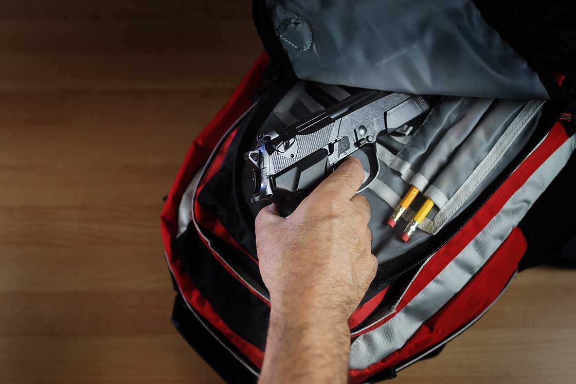 Hand pulling out handgun out of school back-pack