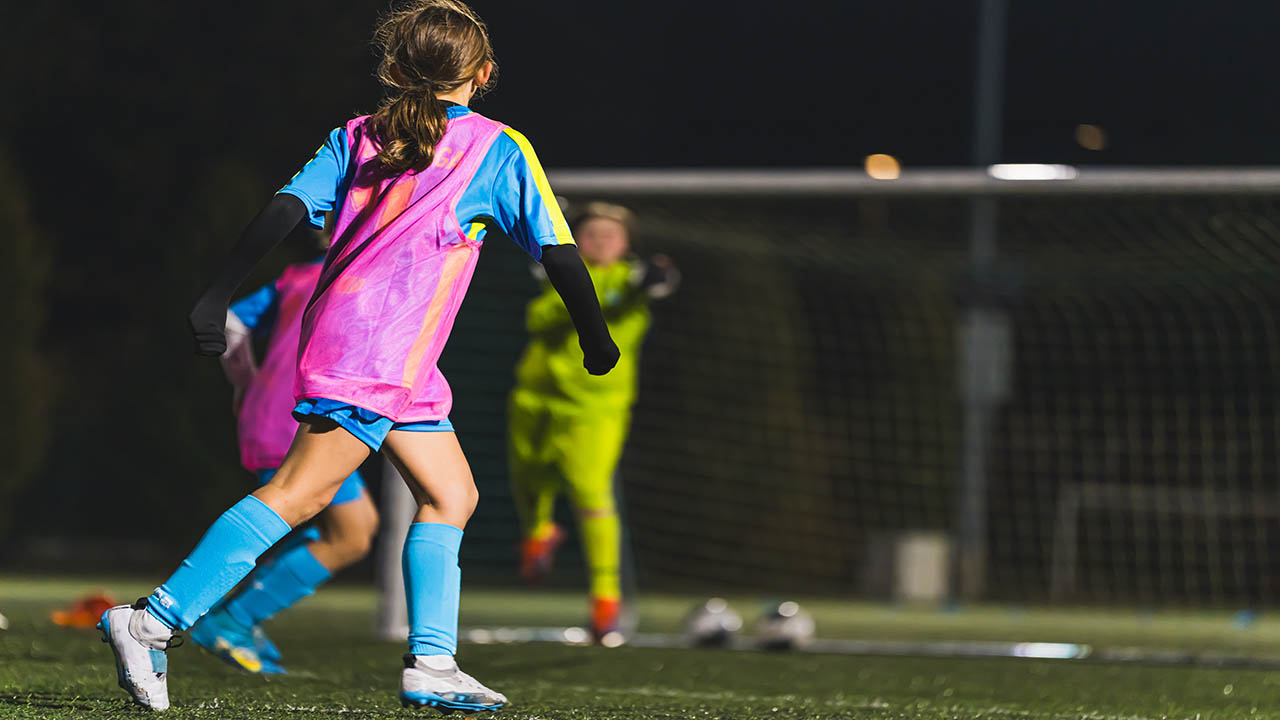 back view of little girls with uniforms playing soccer on the stadium, school soccer team. High quality photo