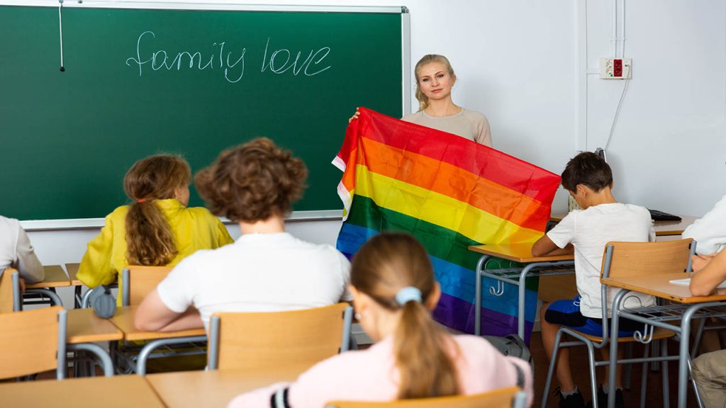 Positive female teacher explaining lgbt theme to children during lesson in class in secondary school