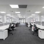 Modern corporate open office in minimalist modern design in whites and greys, empty office workstations